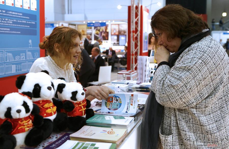 4月8日，在英国伦敦书展上，一位工作人员（左）在中国国家汉办的展台介绍产品。